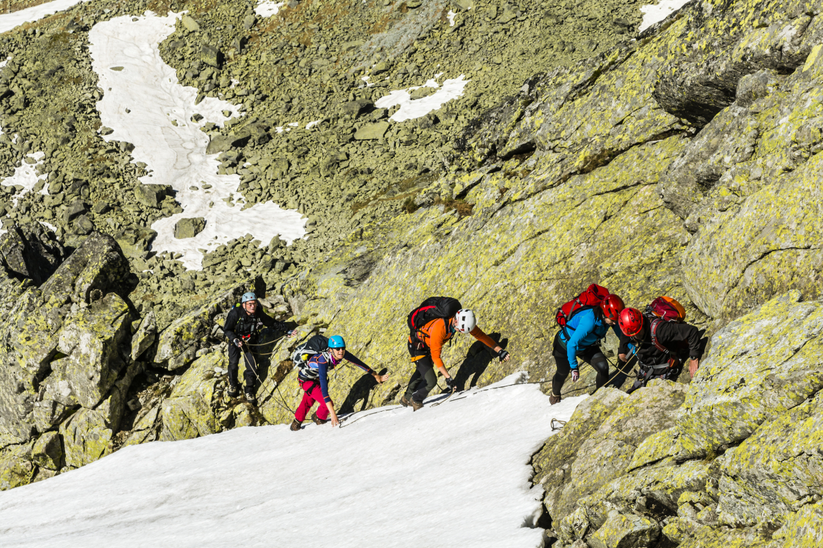 High Tatras, Slovakia - June 18, 2016: Mountain guide with a group of clients when negotiating a snowflake in the Tatras Mountains.